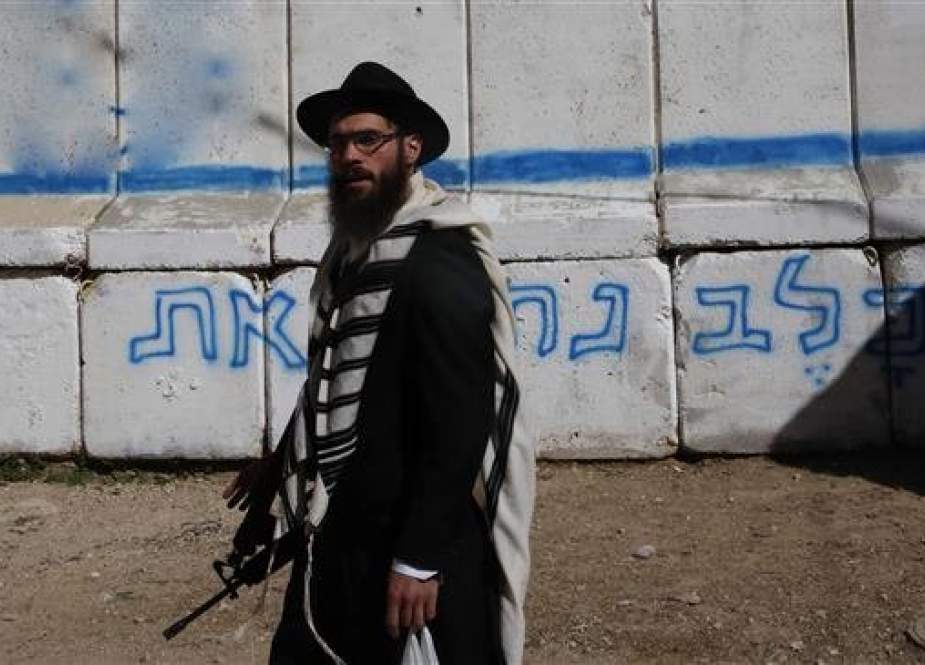 Israeli settler standing guard in the occupied West Bank town of al-Khalil.jpg