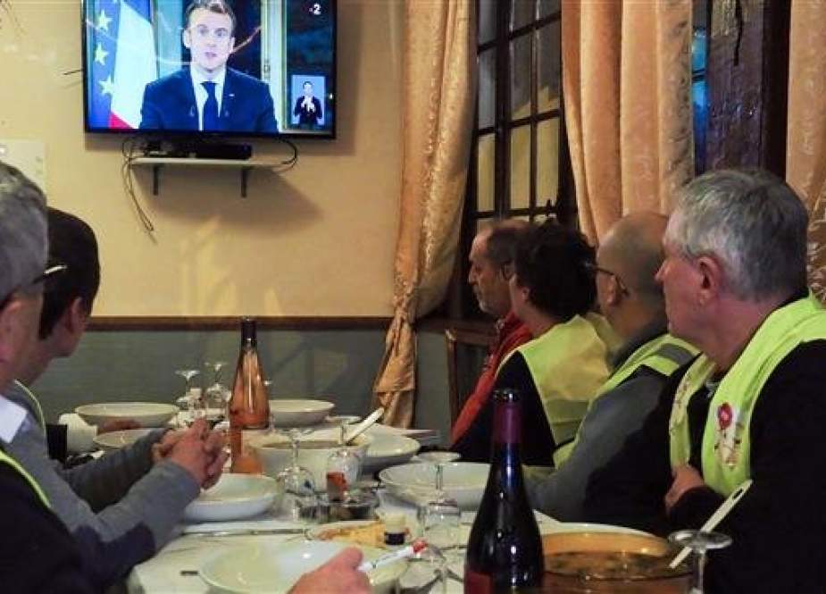 Yellow vest (gilets jaunes) protestors take notes as they watch French President Emmanuel Macron delivering a speech on TV on December 10, 2018. (AFP photo)