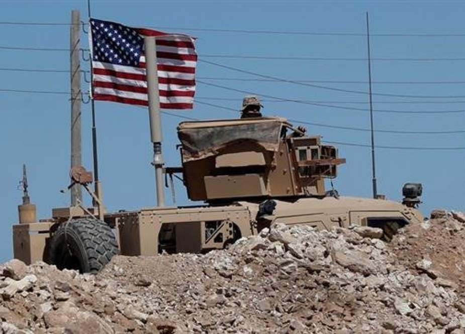A US soldier sits on an armored vehicle behind a sand barrier at a newly installed position near the tense front line between the US-backed Syrian Manbij Military Council and the Turkish-backed militia, in Manbij, north Syria, April 4, 2018. (Photo by AP)