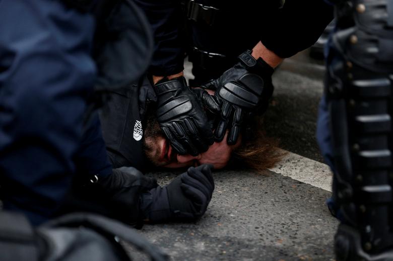 French CRS riot police apprehend a man in a street near Saint Lazare train station during a national day of protest by the 