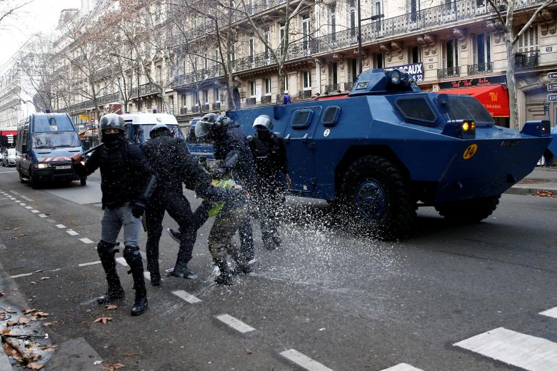 French Gendarmes apprehend a protester as they advance with armored vehicles during clashes at a demonstration during a national day of protest by the 