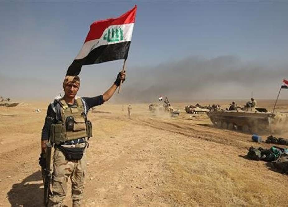 Iraqi forces poses for a photo holding his national flag.jpg