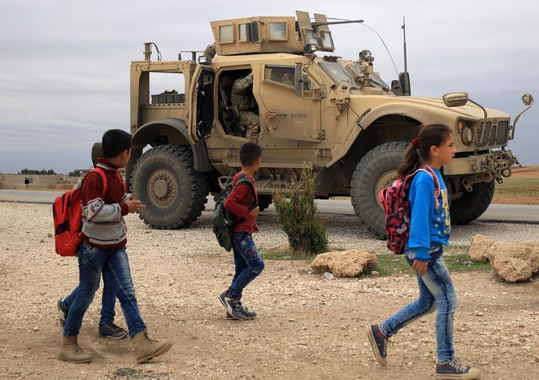 Syrian schoolchildren walk as U.S. troops patrol near Turkish border in Hasakah, November 4, 2018.