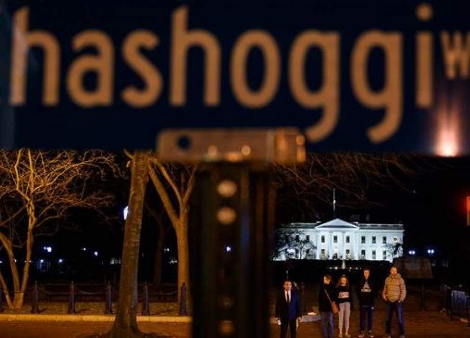 People wait to cross the street near a protest sign reading "Khashoggi way" across the street from the White House in Washington, DC, on December 23, 2018. (Photo by AFP)