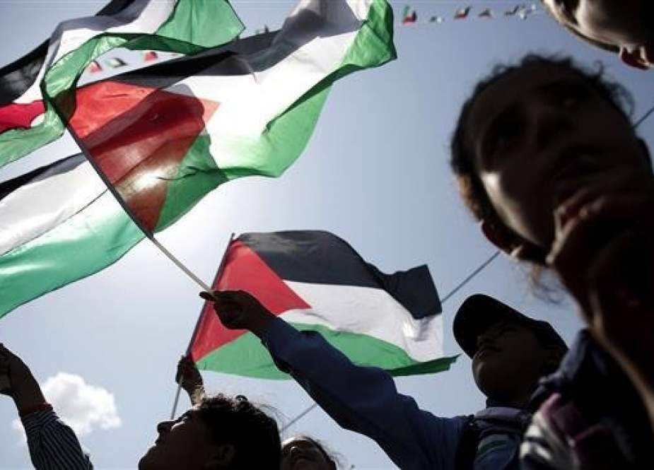 Palestinians wave their flags as they watch a live-screening of President Mahmoud Abbas