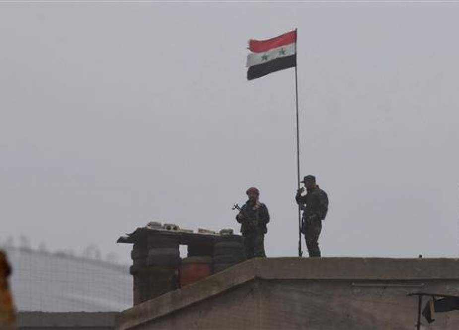 A picture taken on December 30, 2018, shows a Syrian national flag flying over a building as government forces gather in the southern countryside of the northern Kurdish-controlled city of Manbij. (Photo by AFP)
