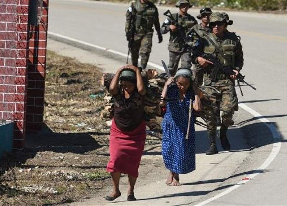 Indigenous women carry firewood on their backs and a group of soldiers walk near Yalambojoch, home village of eight-year-old migrant Felipe Gomez, who died in a medical center in Alamogordo, New Mexico, United States, on December 24, while in custody of US Customs and Border Protection officers, in Nenton municipality, Huehuetenango department, 400 km northwest Guatemala City on December 28, 2018. (AFP photo)