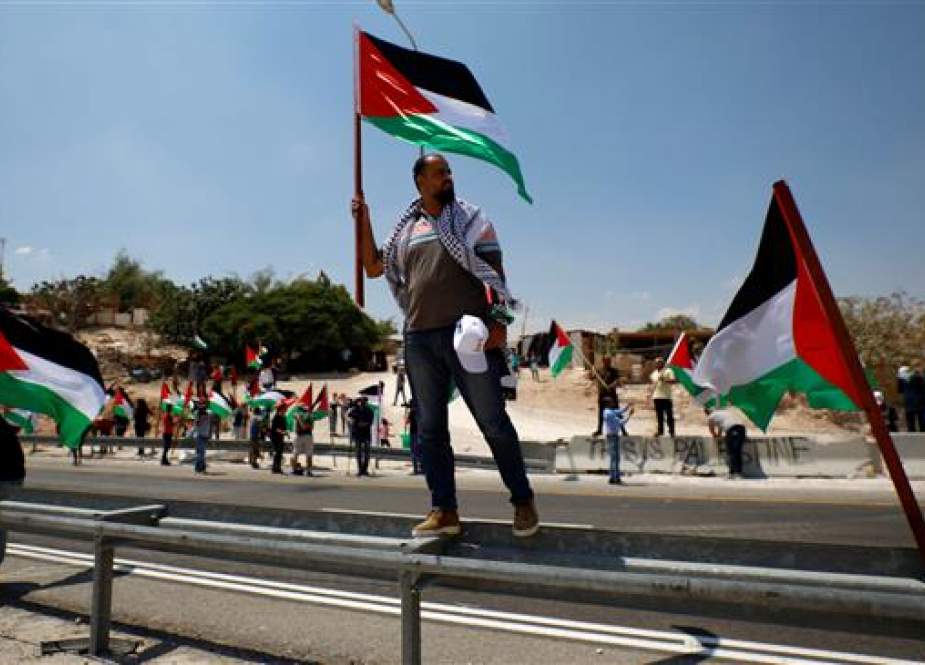 Demonstrator holds a Palestinian flag in the occupied West Bank.jpg