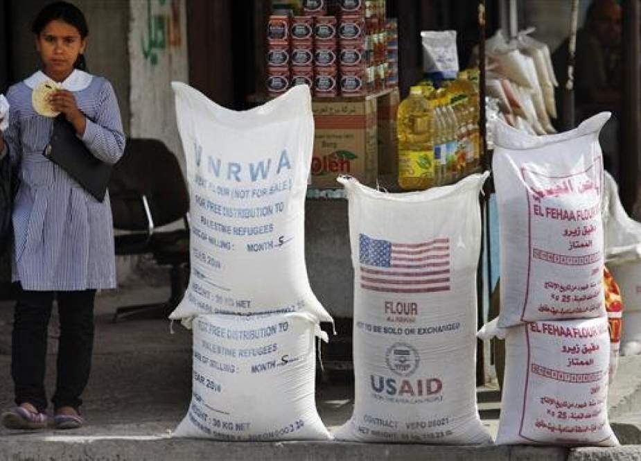 A Palestinian pupil walks past sacks of flour, some part of humanitarian aid by United Nations Relief and Works Agency, (UNRWA) and the US Agency for International Development (USAID), at Shati refugee camp, in Gaza City, June 6, 2010. (Photo by AP)