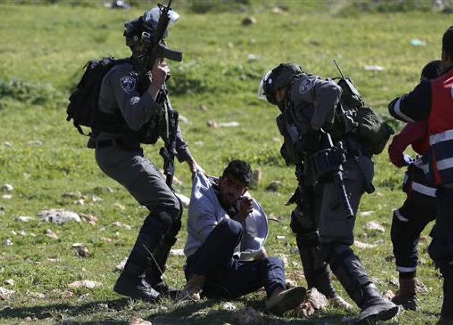 Israeli soldier pulls an injured Palestinian demonstrator in the West Bank town of Birzeit.jpg