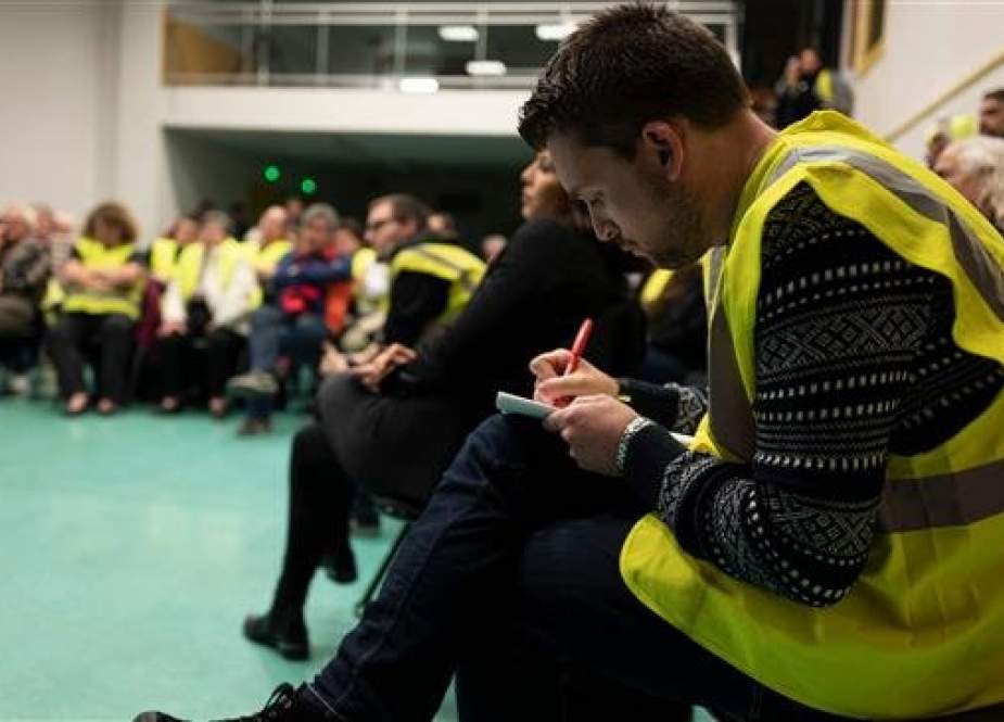 A man wearing a yellow vest takes notes as he attends a meeting called by local members of the “yellow vest” movement, in Ternay, near the French east-central city of Lyon, on January 22, 2019. (Photo by AFP)