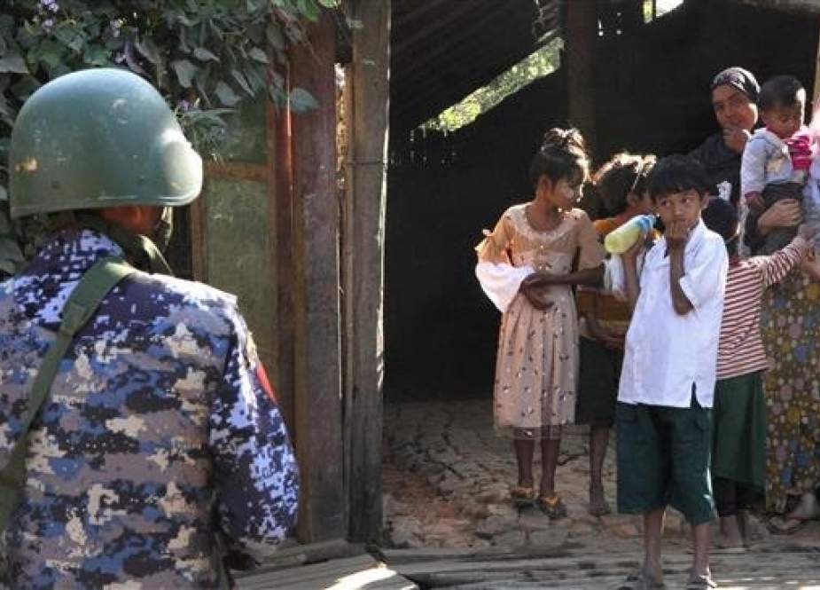 A Myanmar border guard stands near a Rohingya Muslim family in front of their home in a village during a government-organized visit for journalists in Buthidaung Township, in Rakhine State, Myanmar, on January 25, 2019. (Photo by AFP)