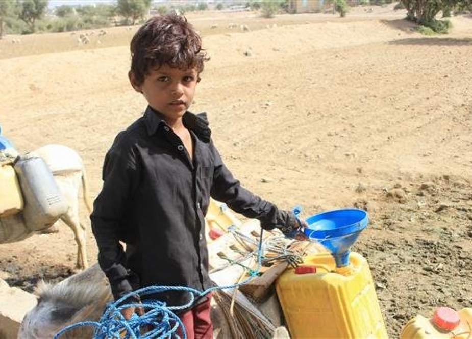 In this undated photo, a Yemeni refugee child fills water jerricans at a camp for displaced people in northern Yemen. (Photo by AFP)