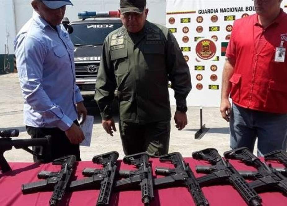 Venezuelan authorities stand next to US-made weapons seized from a cargo plane coming from Miami, Florida. (Photo by Ministry of Interior, Justice and Peace)
