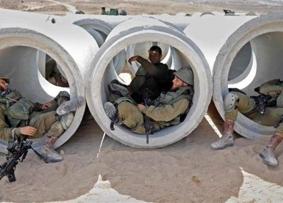 This file photo shows Israeli soldiers lying down and resting in cement pipes during a military exercise at an army base on July 3, 2018. (By AFP)