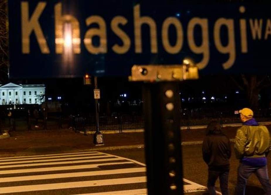 People cross the street near a protest sign reading "Khashoggi way" across the street from the White House in Washington, DC, on December 23, 2018. (Photo by AFP)