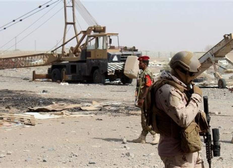 Pro-Saudi forces stand guard outside a damaged warehouse of Yemen