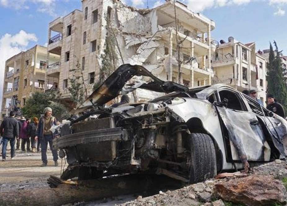 Wreckage of a car and a damaged building are seen in Syria