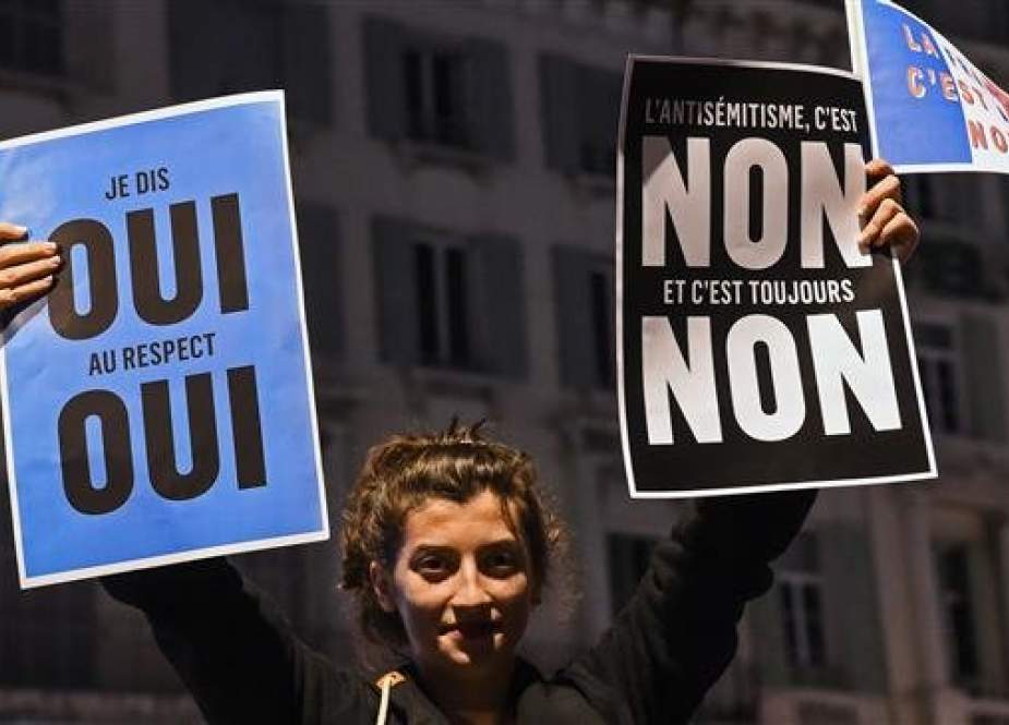 A young woman holds placards as she takes part with others in a rally against anti-semitism on February 19, 2019. (AFP)