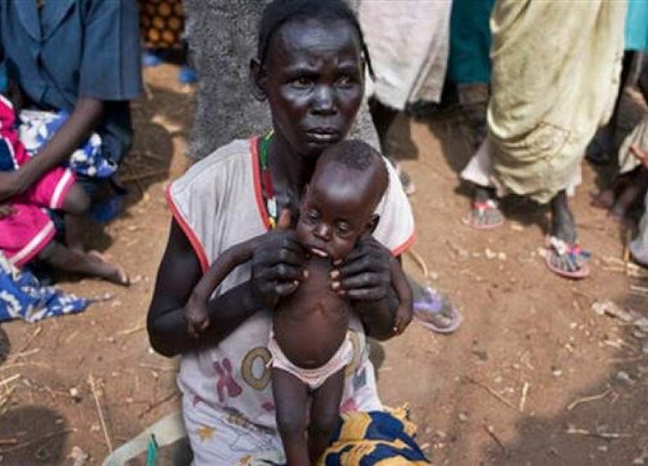 In this file photo taken on April 5, 2017, a mother holds her seven-month-old son as she and others walk to a food distribution site in Malualkuel in the Northern Bahr el Ghazal region of South Sudan. (AP)
