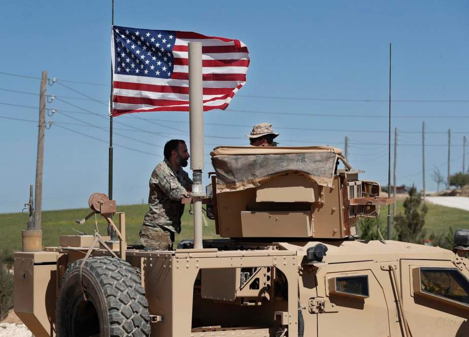 A member of the U.S.-backed Syrian Manbij Military Council, left, speaks with a U.S. soldier in north Syria, on April 4. (Hussein Malla/AP)