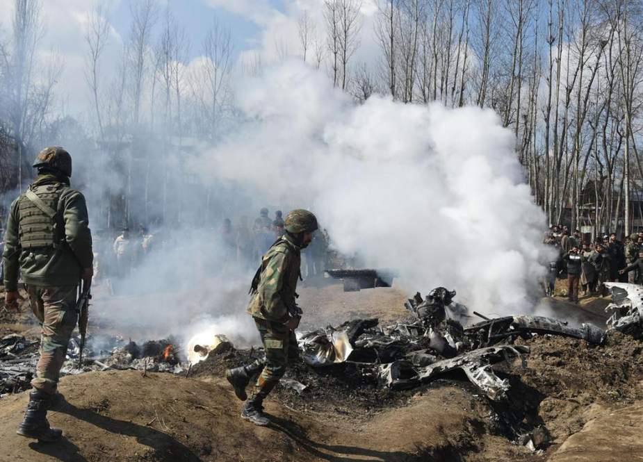 Indian soldiers and Kashmiri onlookers stand near the remains of an Indian Air Force aircraft after it crashed in Budgam district, some 30 kms from Srinagar on February 27, 2019. (Photo by AFP)