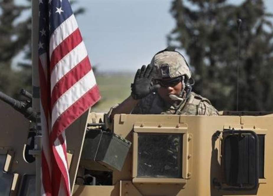 Picture taken on April 4, 2018 shows a US trooper waving as he sits on an armored vehicle on a road leading to the town of Manbij in northern Syria. (By AP)