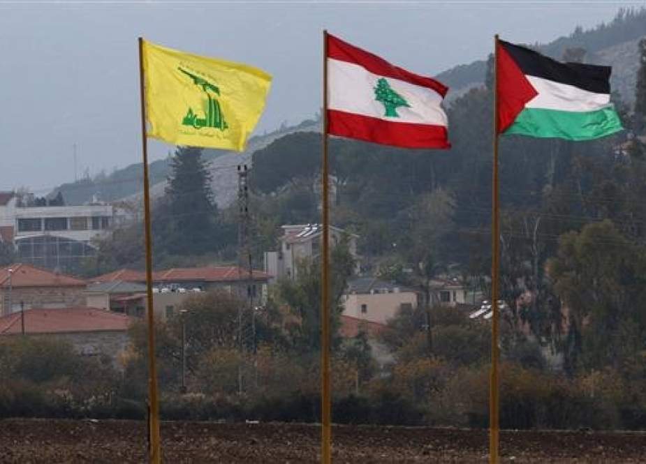 This picture taken on December 4, 2018 shows the flags of the Lebanese Shiite movement Hezbollah (L), Lebanon (C), and Palestine flying near the southern Lebanese village of Kfar Kila near border with Israel. (Photo by AFP)