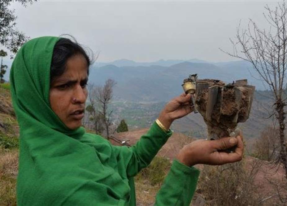 A woman holds a fin of an exploded mortar that locals say was fired by Pakistani troops in Patri village in India