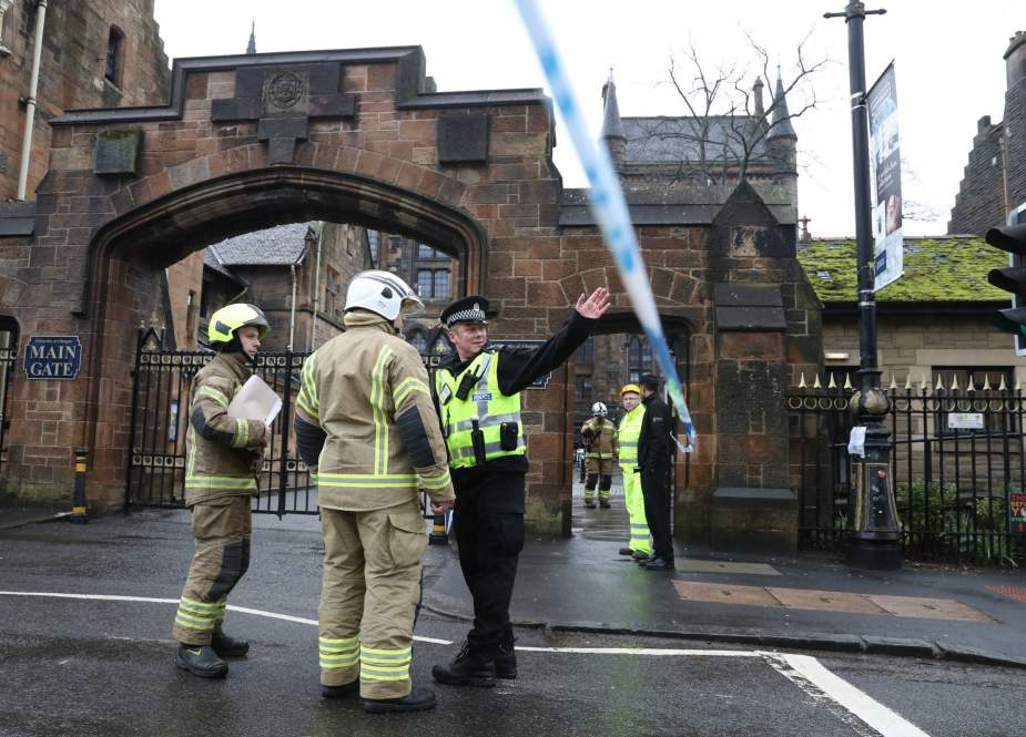 This March 6, 2019 photo published on the website of the Sky News shows Scottish firefighters at the gate of the University of Glasgow in Scotland where police reported the discovery of a parcel bomb earlier in the day.