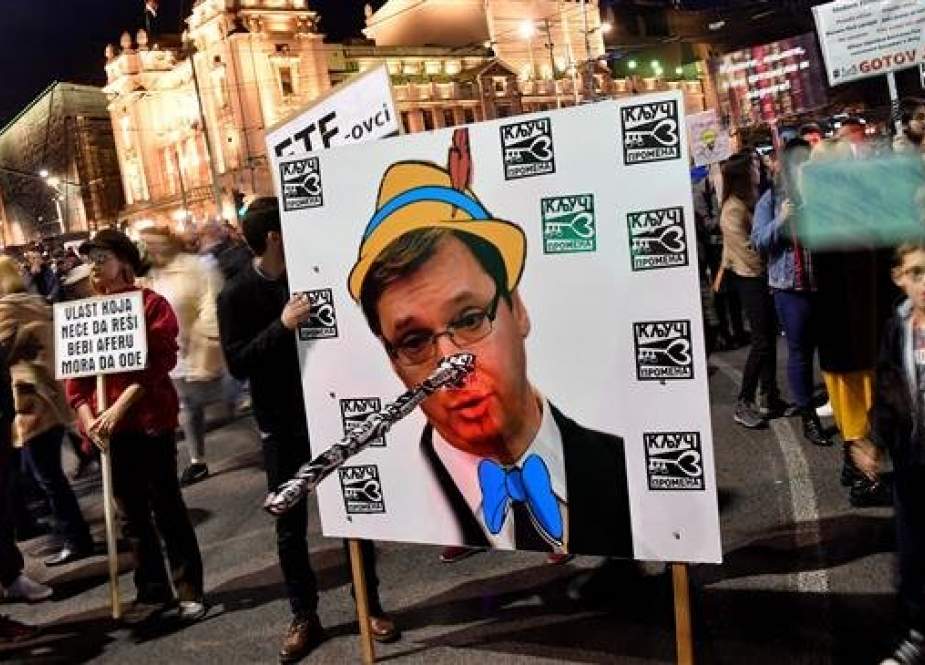 Protesters hold a poster bearing a portrait of Serbian President Aleksandar Vucic with Pinocchio