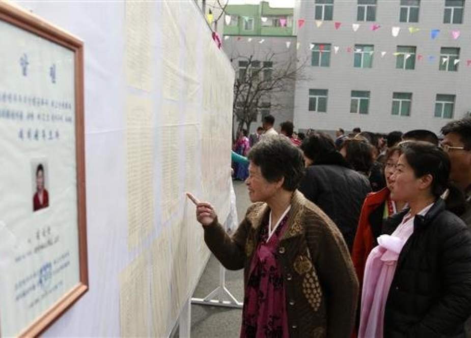 People inspect the list of voters next to a portrait of the only candidate in North Korea’s legislature election.