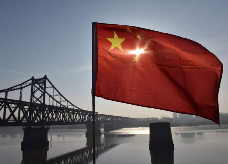 The Chinese flag flies on the Yalu River Broken Bridge, with the Sino-Korean Friendship Bridge, and the North Korean city of Sinuiju behind, in the border city of Dandong, in China