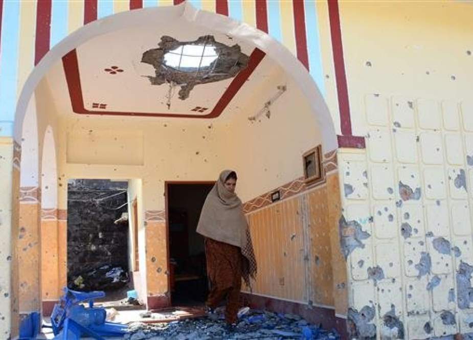 This picture taken on March 5, 2019 shows Pakistani Kashmiri resident Sakina Bibi walking past debris in her house damaged in cross-border shelling in Dhanna village near the Line of Control (LoC) in Pakistan-administered Kashmir. (Photo by AFP)