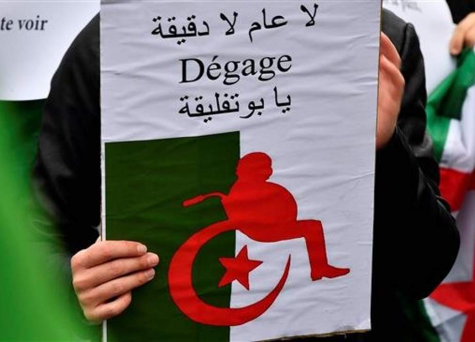 A demonstrator holds a poster representing a silhouette of Algeria