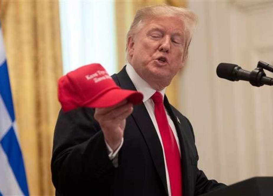US President Donald Trump holds up a hat that says "Make America Great Again," in Greek, as he speaks during a reception in honor of Greek Independence Day in the East Room of the White House in Washington, DC, on March 18, 2019. (Photo by AFP)