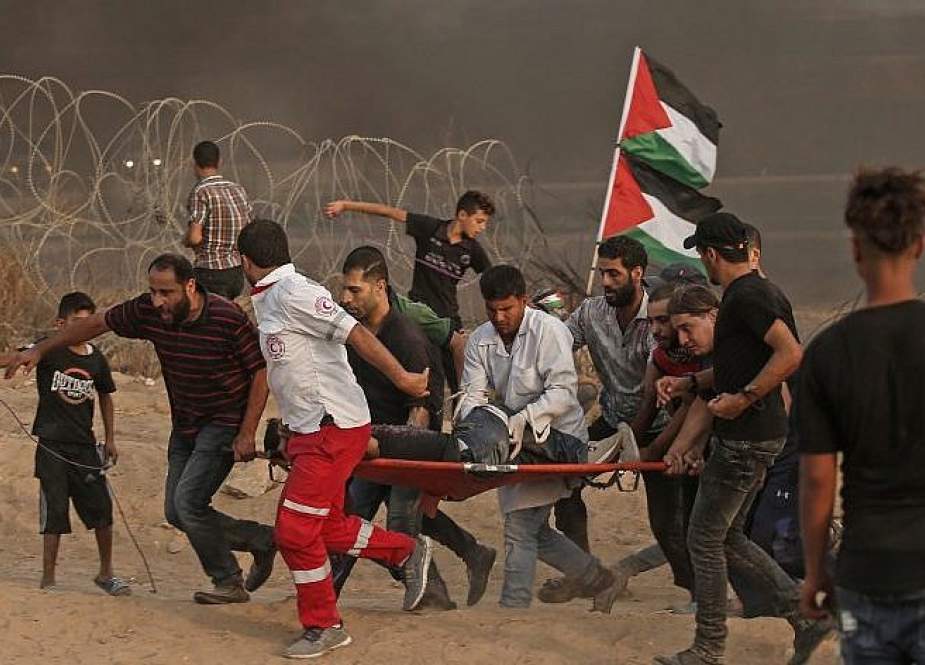 In this file photo taken on October 05, 2018 Palestinian paramedics carry a wounded protester during clashes with Israeli forces east of Gaza city, along the Gaza fence.