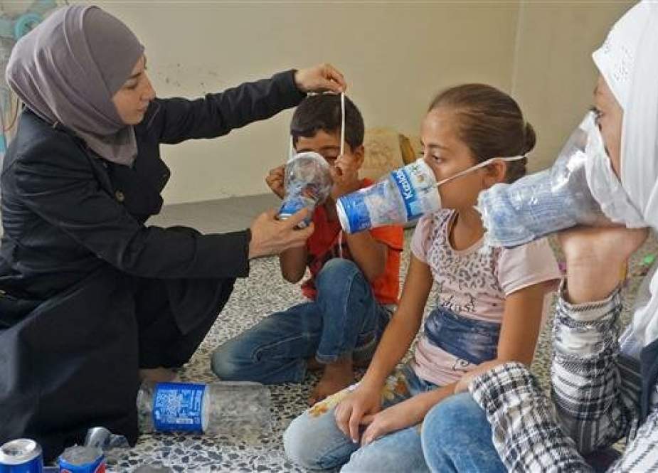 Um Majid tries an improvised gas mask on her family members in Binnish, Idlib Province, Syria.jpg