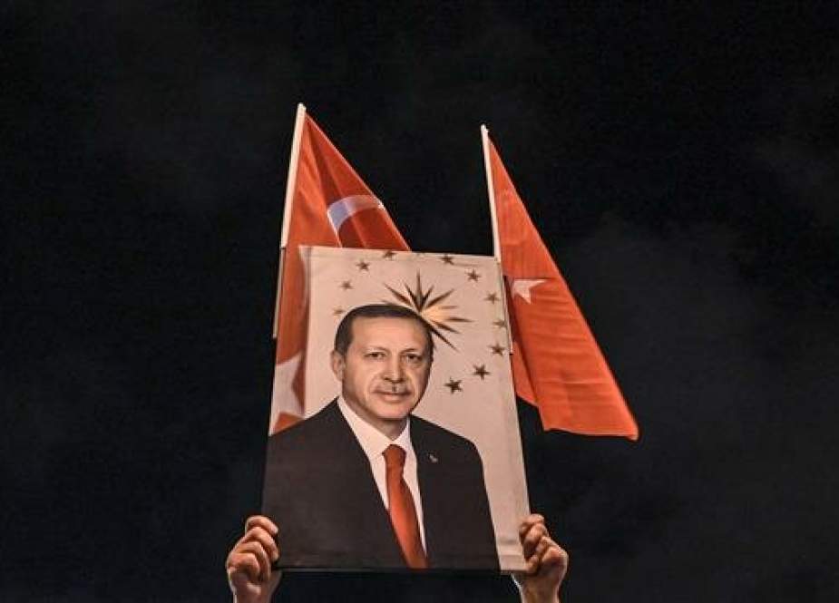 A supporter of Justice and development party (AKP) holds a banner picturing Turkish president Recep Tayyip Erdogan during a rally near the headquarters of the conservative AKP party on March 31, 2019 in Istanbul after the non-definitive results of the local elections to elect the mayors for 30 large metropolitan cities, 51 provincial capitals and 922 districts. (Photo by AFP)