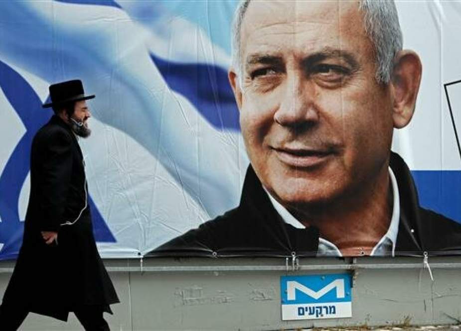 An ultra-Orthodox Jewish man walks past a portrait of Israeli Prime Minister Benjamin Netanyahu.jpg