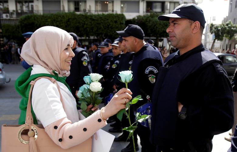 A demonstrator offers a flower to a police officer as teachers and students take part in a protest demanding immediate political change in Algiers, March 13