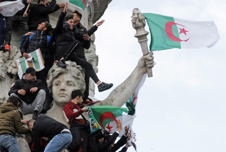Protestors hold Algerian flags as they attend a demonstration against Algeria's President Abdelaziz Bouteflika on the Place de la Republique, in Paris, France, March 10