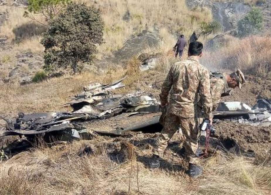 Pakistani soldiers stand next to the wreckage of an Indian fighter jet.jpeg