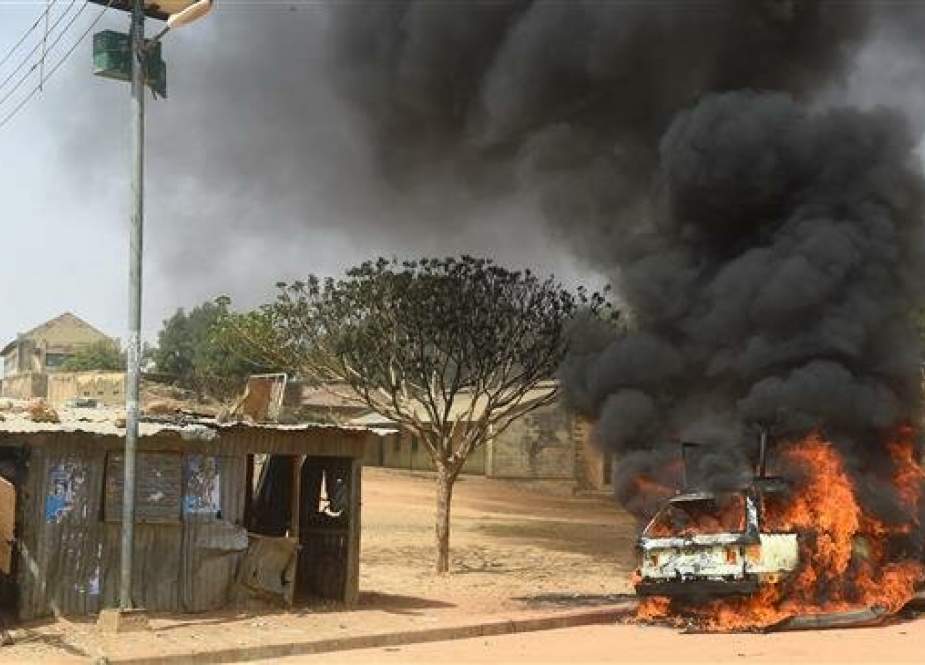 A man tries to run away from a rickety road side shop as cars are set on fire following deadly clashes between supporters of the ruling All Progressives Congress (APC) and the opposition Peoples Democratic Party (PDP) at Kofa in Bebeji district of Kano, economic nerve centre of northern Nigeria, on February 22, 2019. (Photo by AFP)