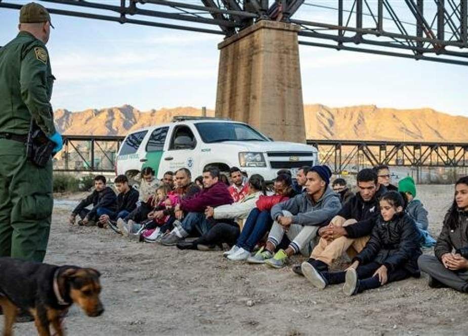 A group of about 30 Brazilian migrants sit on the ground on the US-Mexico border in Sunland Park, New Mexico on March 20, 2019. (AFP photo)