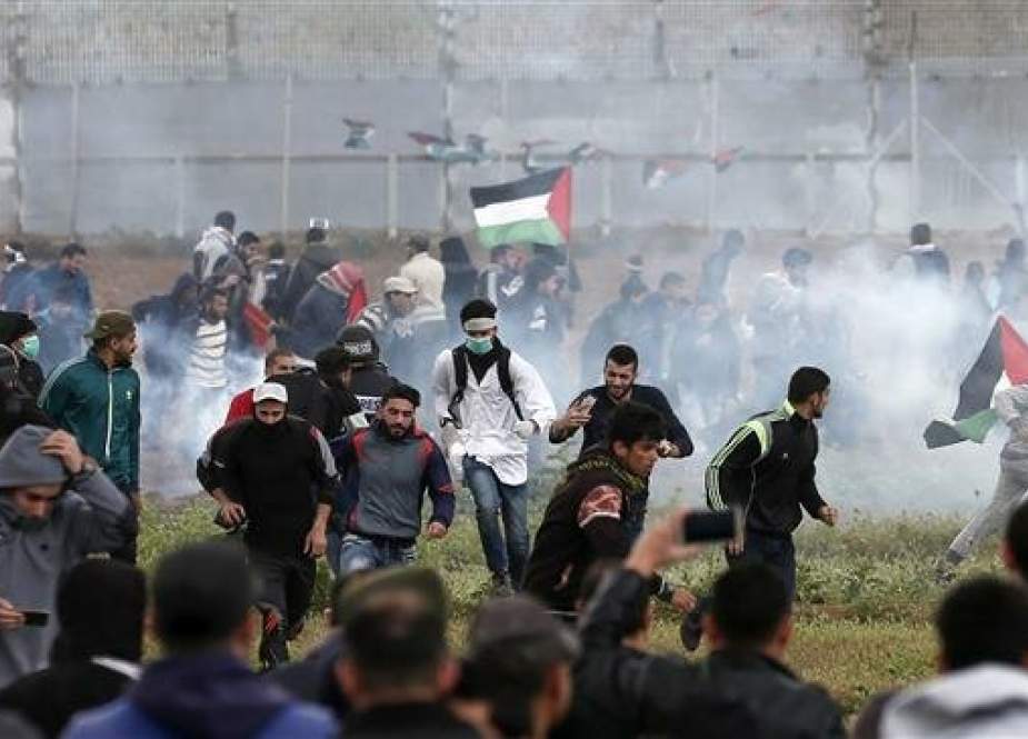 Palestinian protesters run for cover from tear gas canisters fired by Israeli forces during clashes following a demonstration marking the first anniversary of the March of Return protests, near the border with the occupied territories east of Gaza City on March 30, 2019. (Photo by AFP)