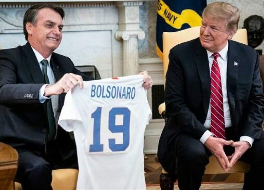 President Donald Trump (R) presents Brazilian President Jair Bolsonaro with a US national team soccer jersey during a meeting in the Oval Office of the White House, March 19, 2019, in Washington. (Photo by AP)