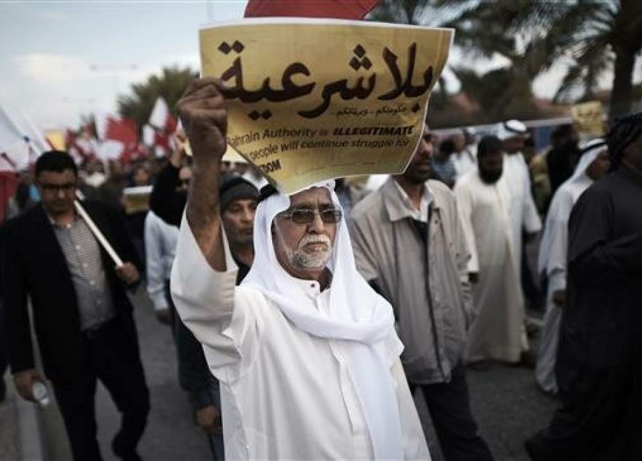 This file photo shows a Bahraini man holding up a placard reading in Arabic "Your government and your parliament are without legitimacy" during an anti-government protest in the village of Jannusan, west of the capital Manama. (Photo by AFP)