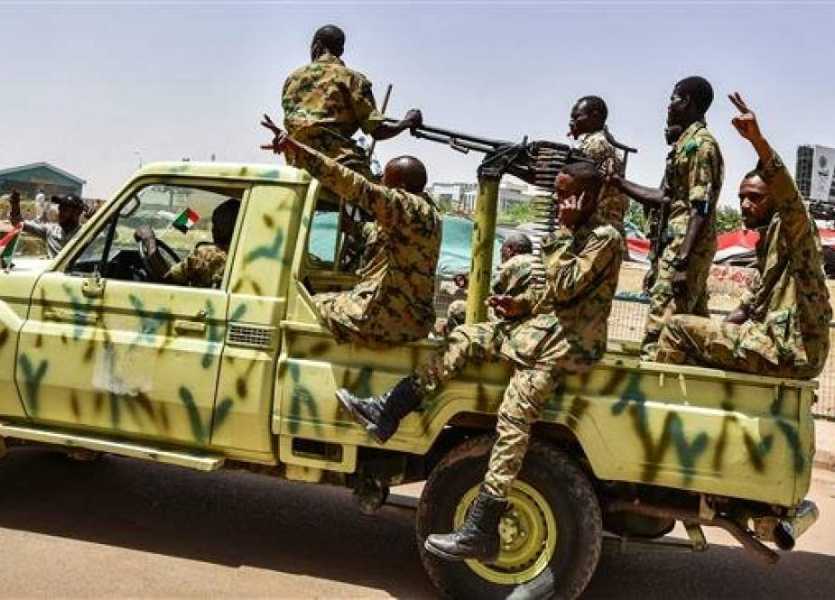 Sudanese soldiers flash the victory gesture as they sit in the back of a technical (pickup truck mounted with a turret) nearby a scene of demonstrators gathering outside the army headquarters in the Sudanese capital Khartoum on April 13, 2019. (Photo by AFP)