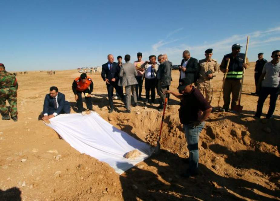 Para anggota Pertahanan Sipil dan pejabat Irak menutupi tulang-belulang dari kuburan massal Kurdi yang digali di sebelah barat kota Samawa, Irak. (Foto Reuters)